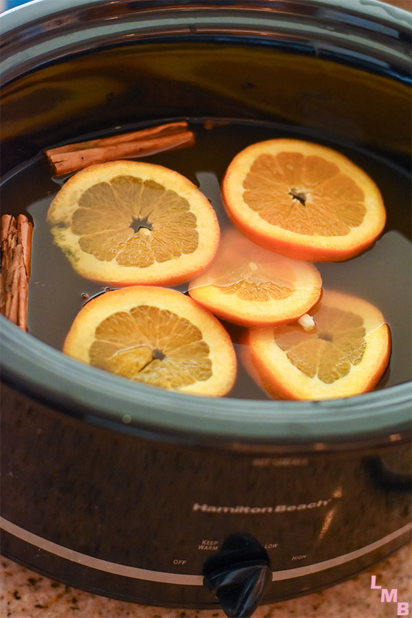 apple cider made in the crockpot with orange slices and cinnamon sticks